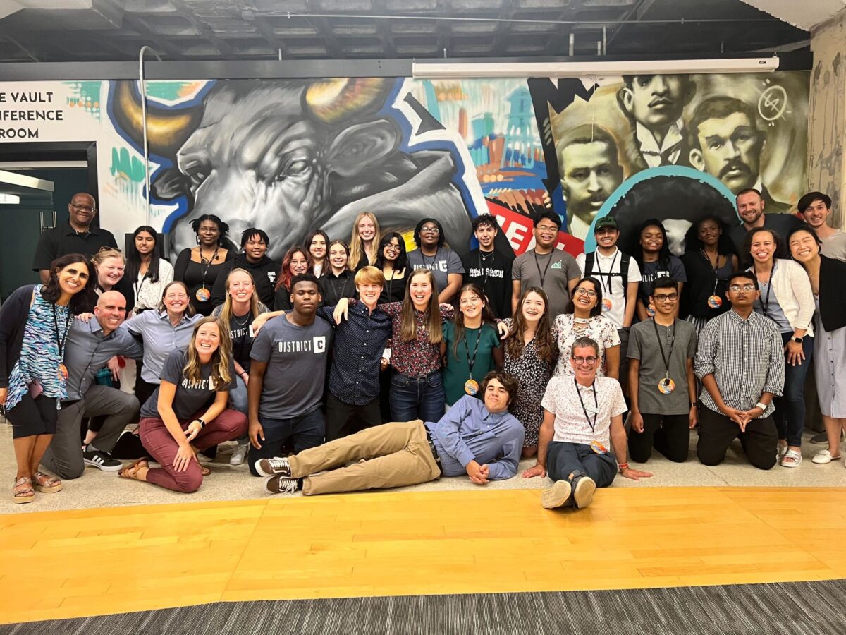 high school students posing for group phot in front of bull mural