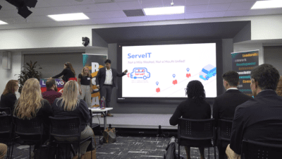 students standing inf front of a projector screen in a small multipurpose room.