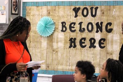 teacher in front of buildboard with three small students