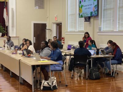 People sitting at tables listening to presenter.