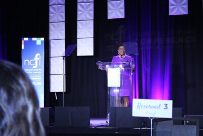 woman standing behind podium and infront of ncfl banner