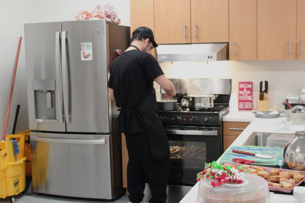 student stirring hot pot on a stove in a kitchen with a cake on the counter