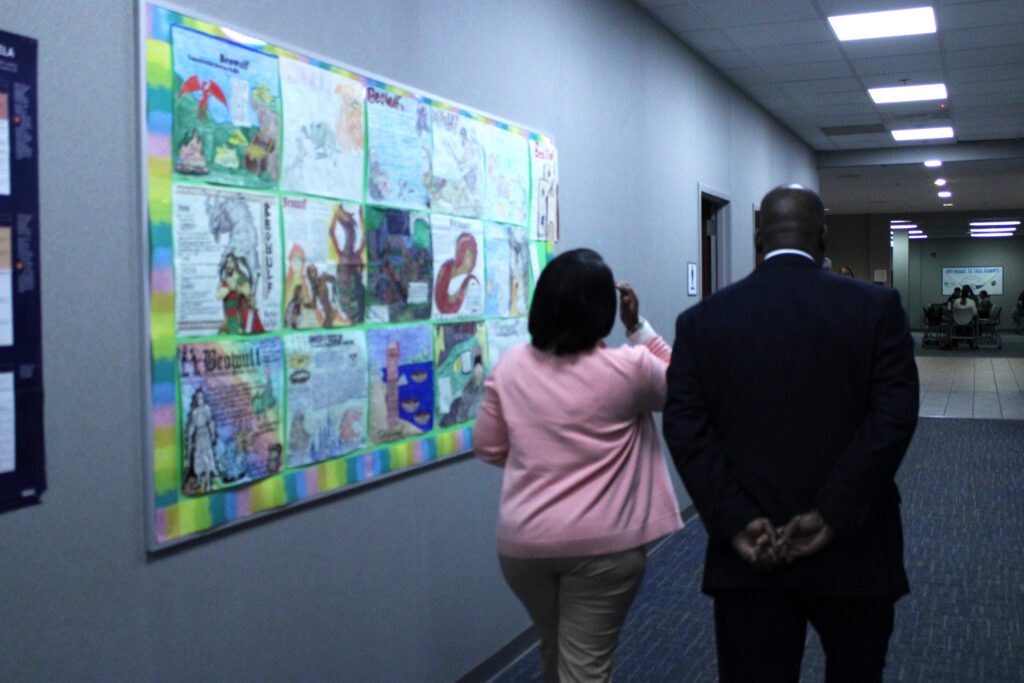 principal walking past student drawings in the hallway