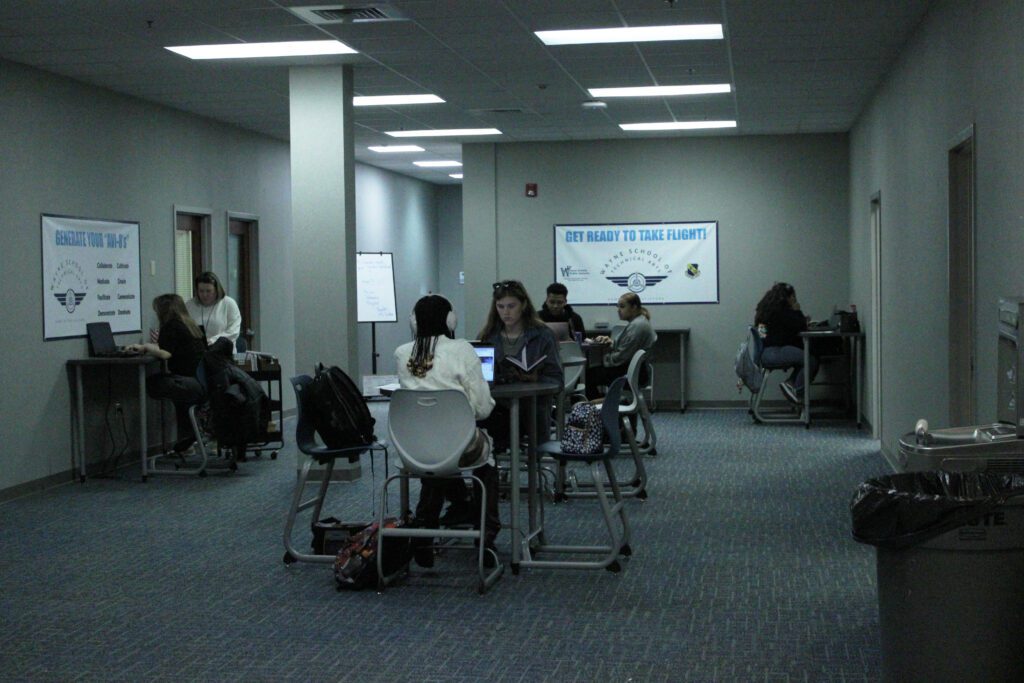 students sitting at high tables in the main lobby of the second floor on computers