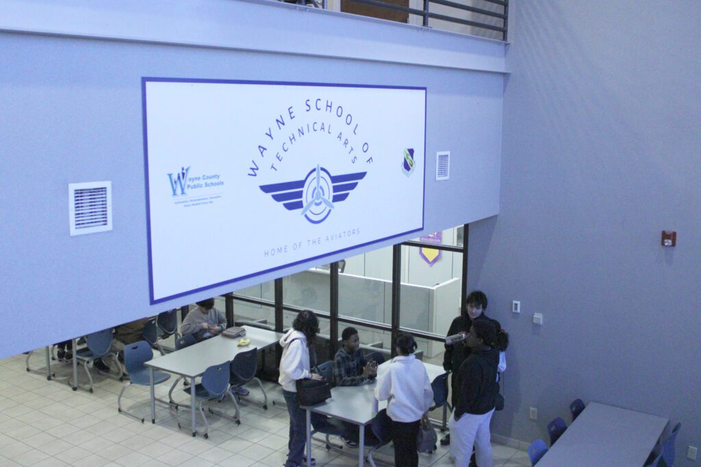 students at long tables in front of the school main office